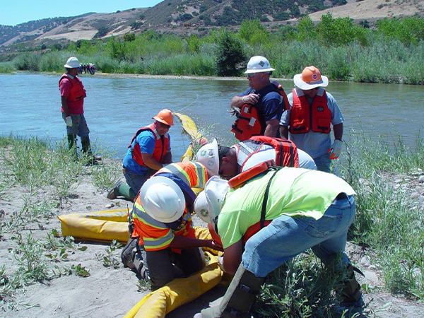 Patriot Environmental Services field technicians deploy boom to contain oil spilled in a river