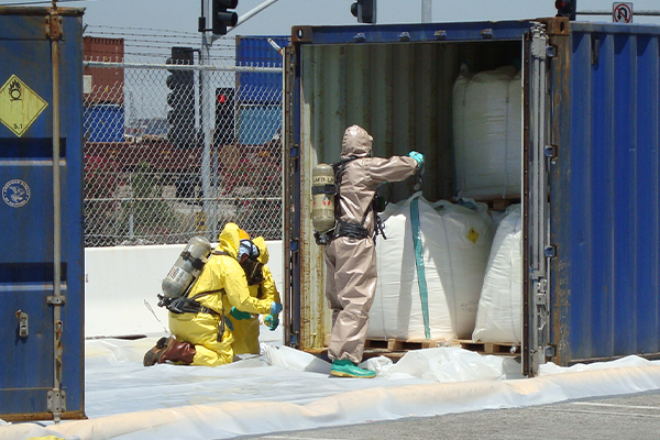 Three Patriot Environmental Services’ employees wearing hazmat suits and SCBA tanks respond to a leaking shipping container