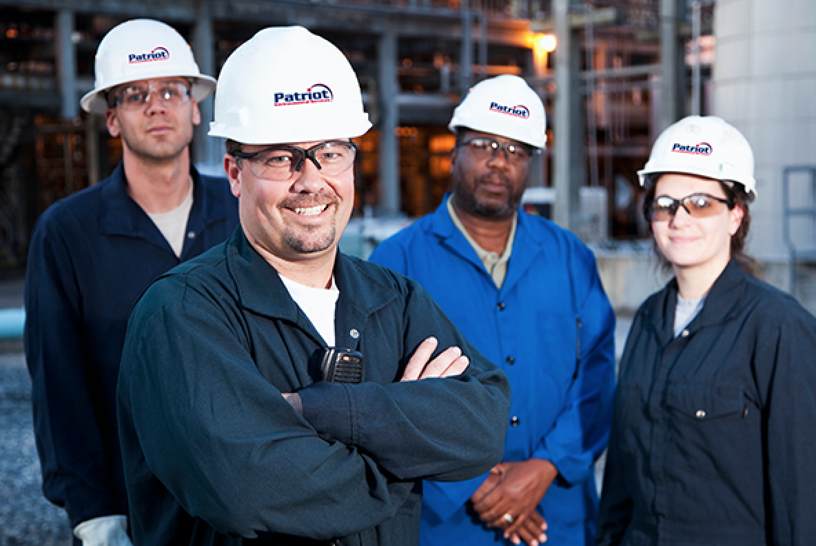 A diverse group of Patriot Environmental Services field technician wearing company uniforms and safety helmets