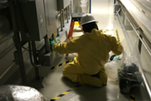 A Patriot Environmental Services technician performing decontamination work in a manufacturing facility