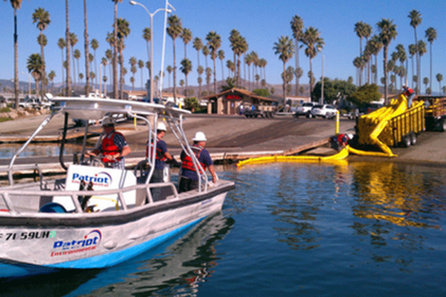 Patriot Environmental Services OSRO employees in a boat deploy containment boom during an inland water spill drill