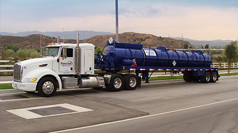 A Patriot Environmental Services specialized vacuum truck drives down the highway